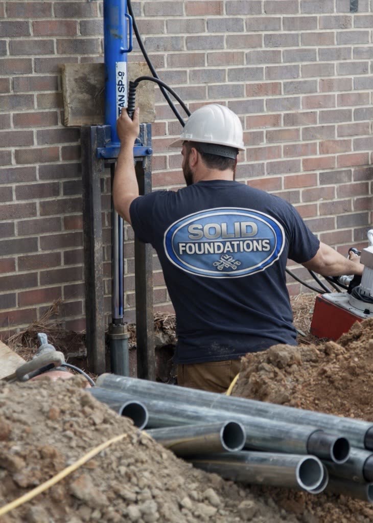 Push pier installation at a foundation repair job site