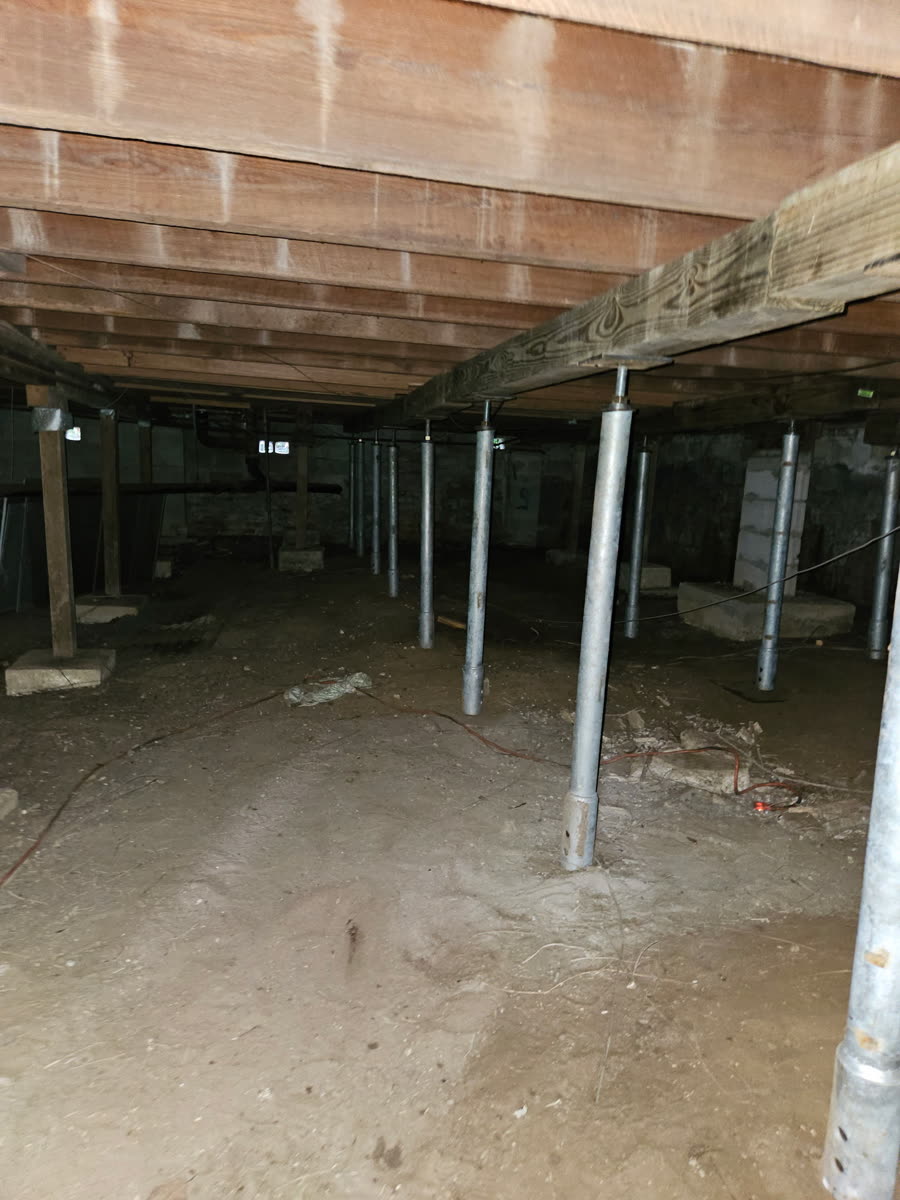 Crawl space with steel support jacks installed under floor joists