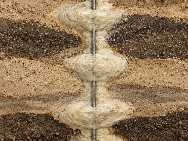 Cutaway illustration of polyurethane foam expanding through soil layers around an injection rod during compaction grouting